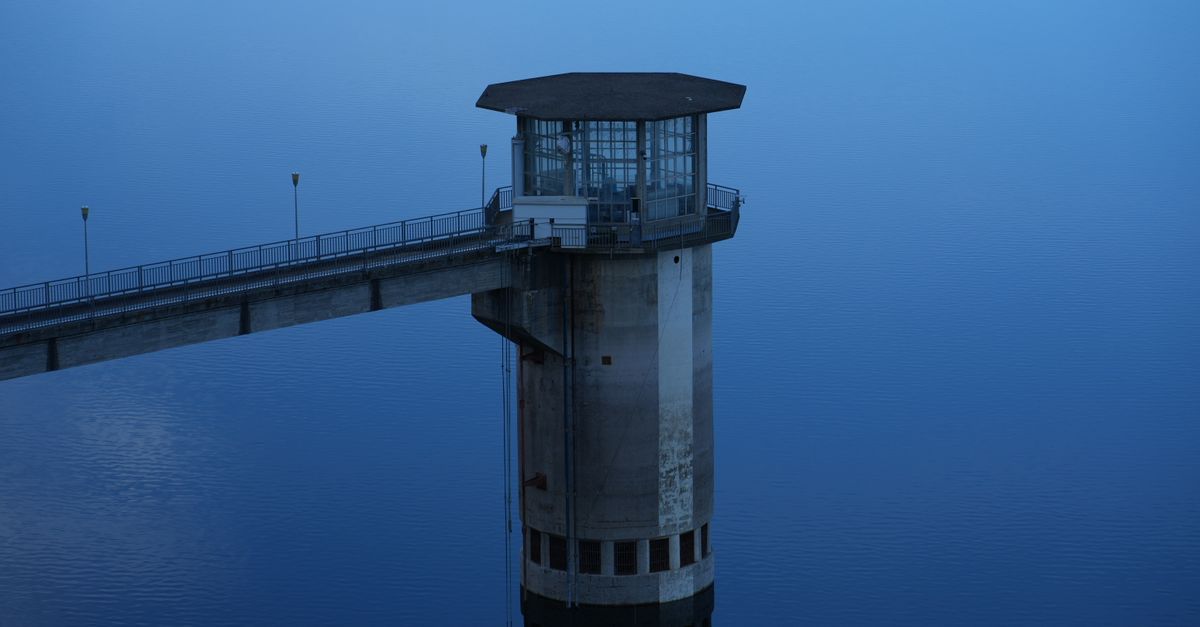 A bridge with a control tower over a body of water.