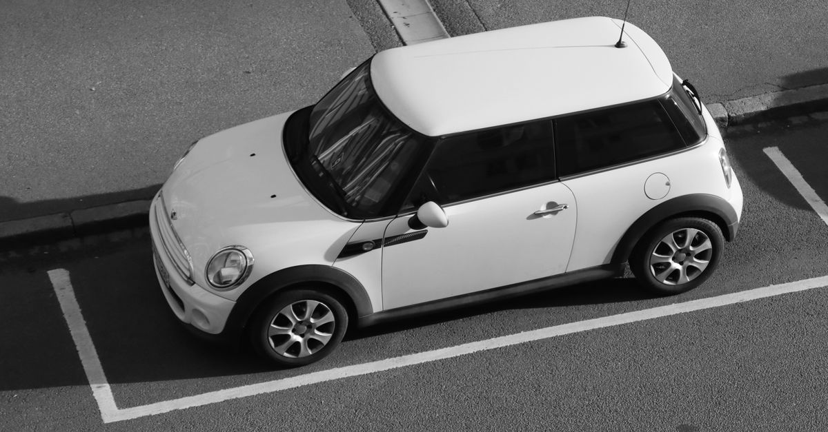 A white Mini Cooper parked in a parking space.