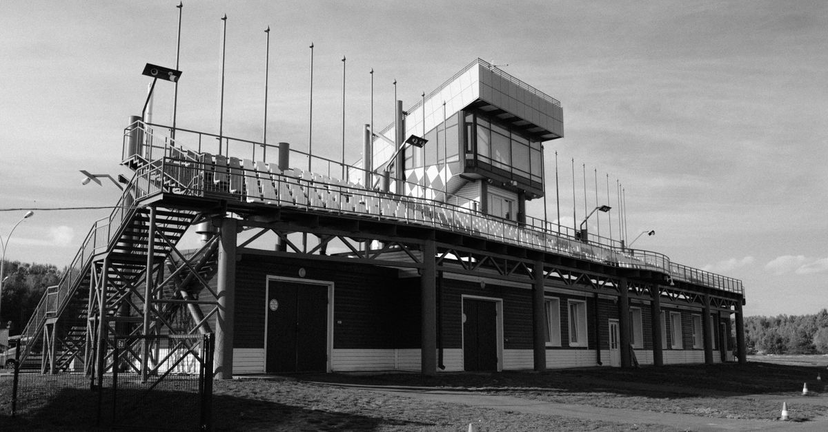 Monochrome photo of an empty racing circuit stand with a control tower.