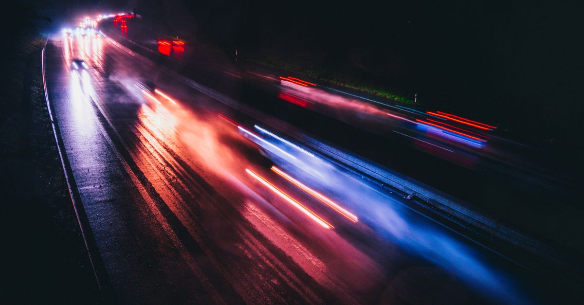 Long-exposure light trails of traffic on a wet road at night