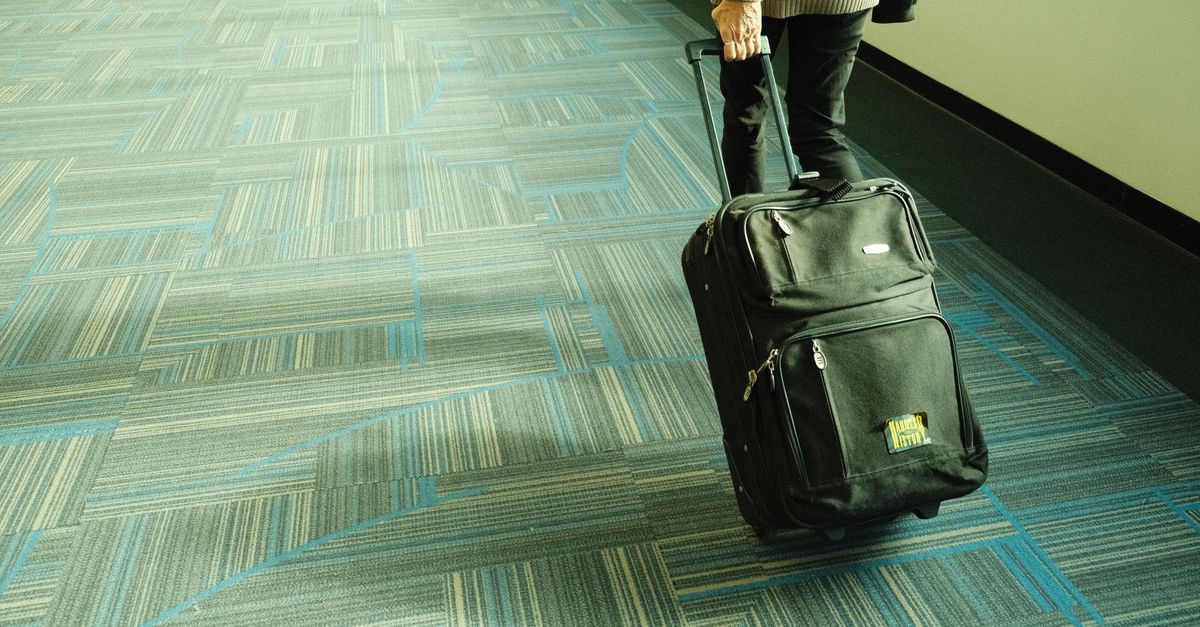 Traveller wheeling a suitcase down an airport corridor