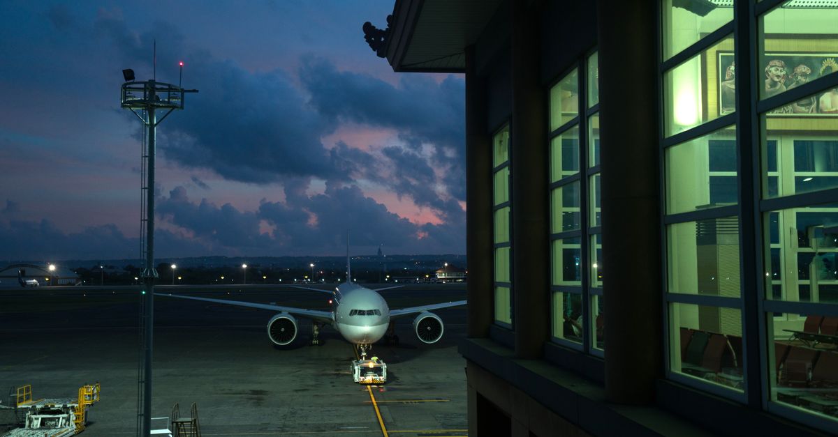 Modern plane parking on stand near assigned gate in modern airport terminal at night