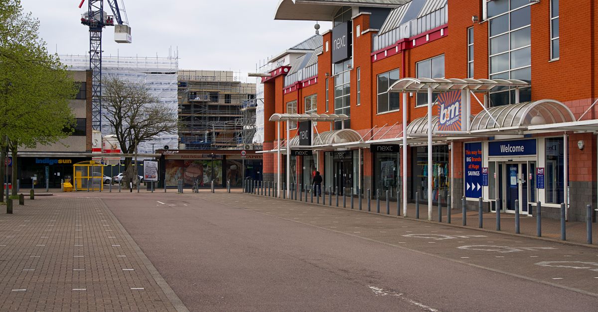View of a modern shopping center with retail stores on a cloudy day in England, highlighting urban architecture.
