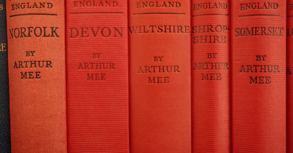A close-up view of vintage books titled 'The King's England' by Arthur Mee, showcasing various English counties.