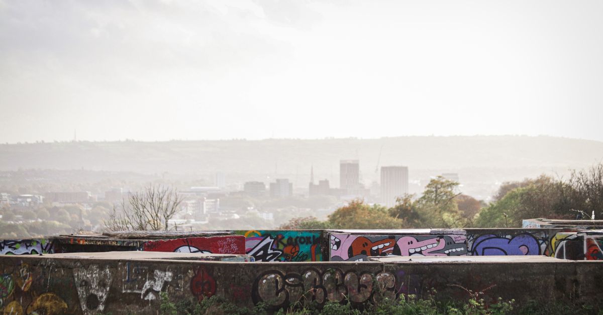 Vibrant graffiti art on an urban wall in Bristol with a city skyline backdrop.