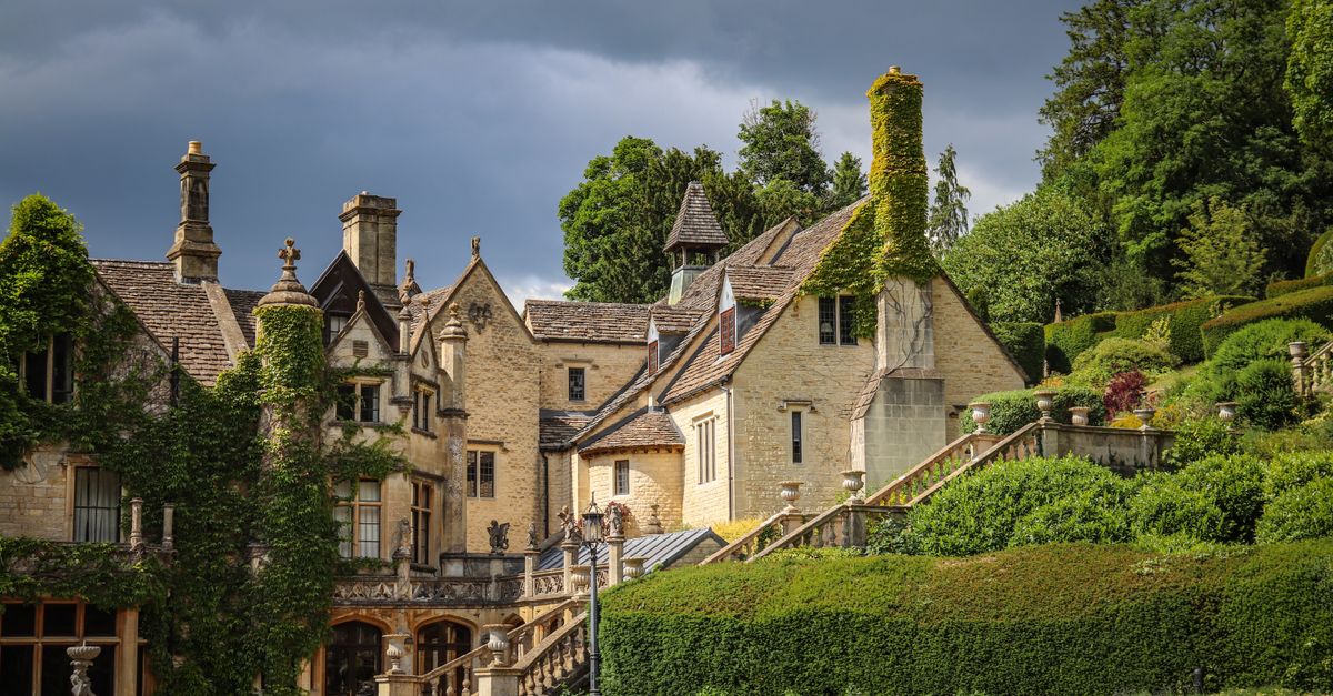 Scenic view of a historic manor house surrounded by lush green gardens in Castle Combe, England.
