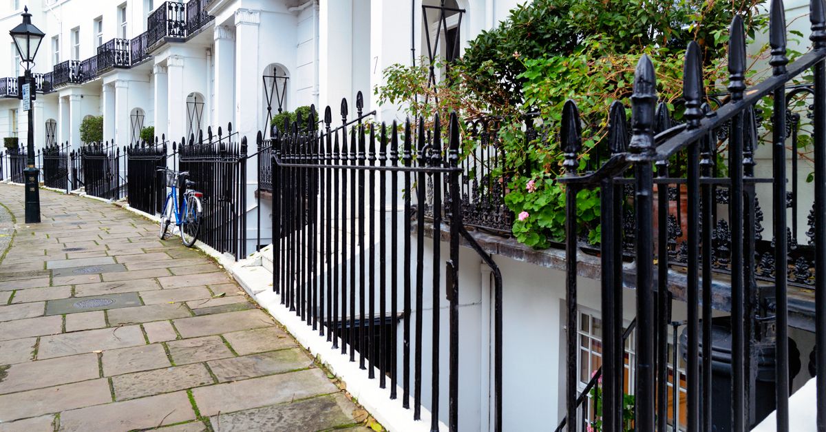 A white Regency terrace with black iron railings and balconies, evoking Cheltenham's spa-town architecture.
