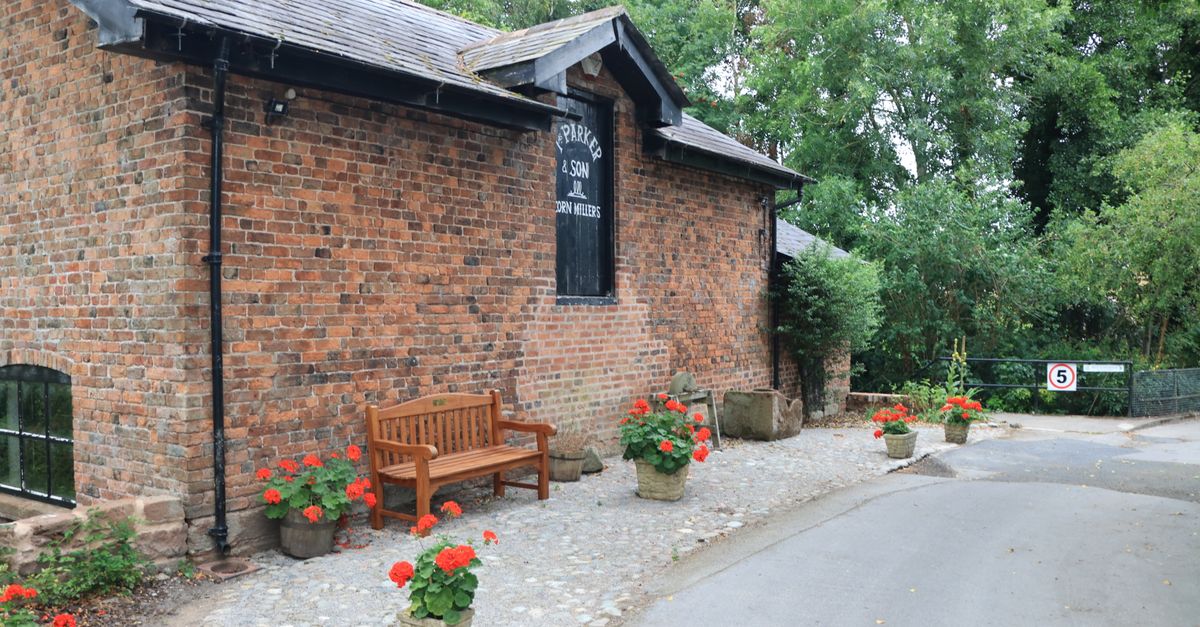Historic brick building with lush greenery in Bunbury, England.