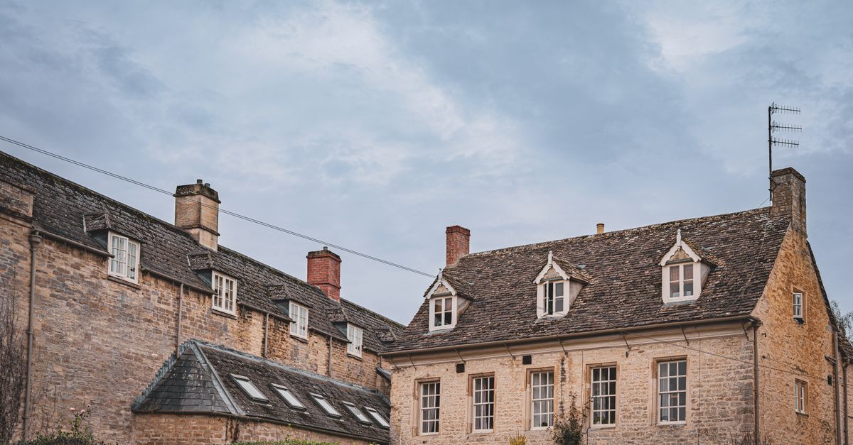 Traditional stone houses in the English countryside under a cloudy sky.