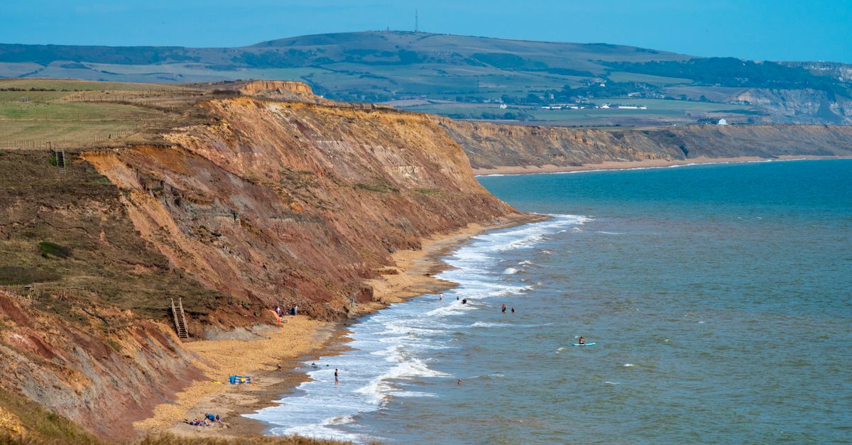 A breathtaking view of rugged coastal cliffs meeting the turquoise sea on a sunny day.