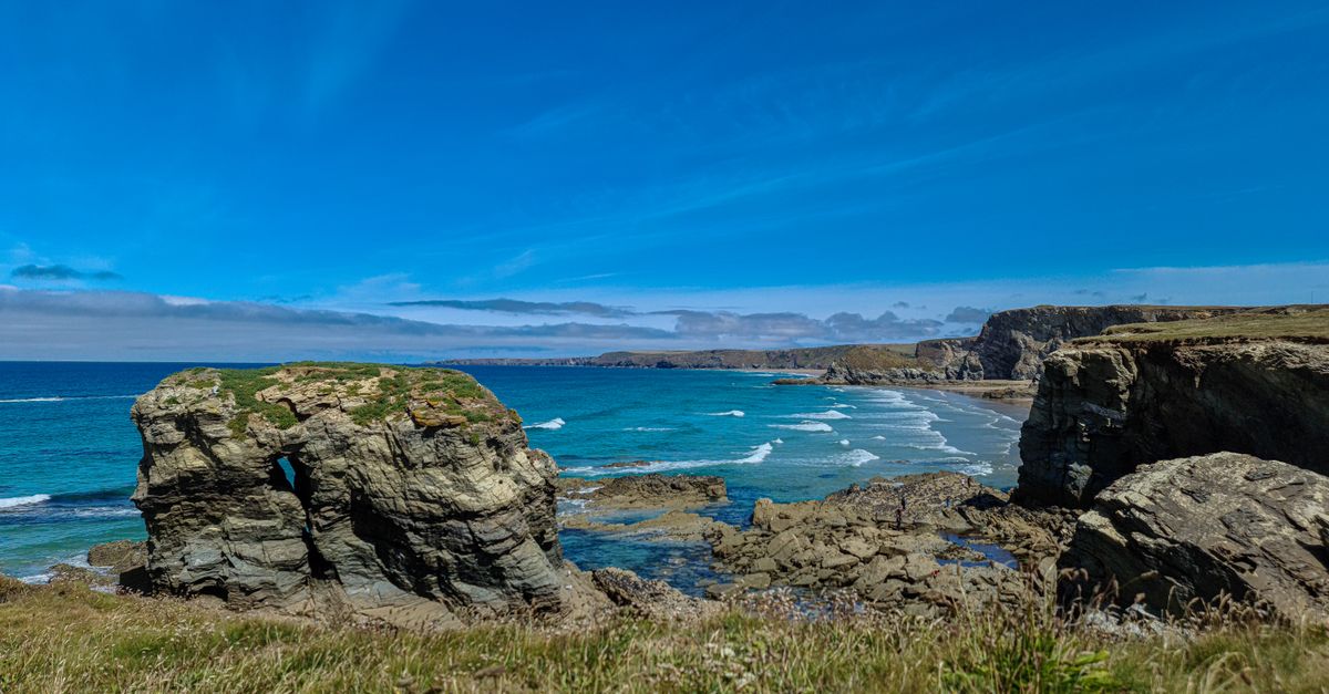 Explore the stunning coastal cliffs and azure sea in Newquay, England under a vivid blue sky.