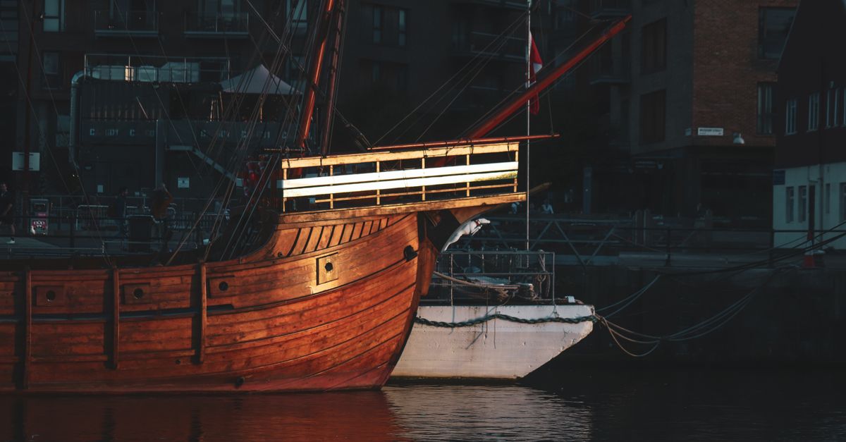A historic wooden ship beautifully illuminated in Bristol's harbor at night.