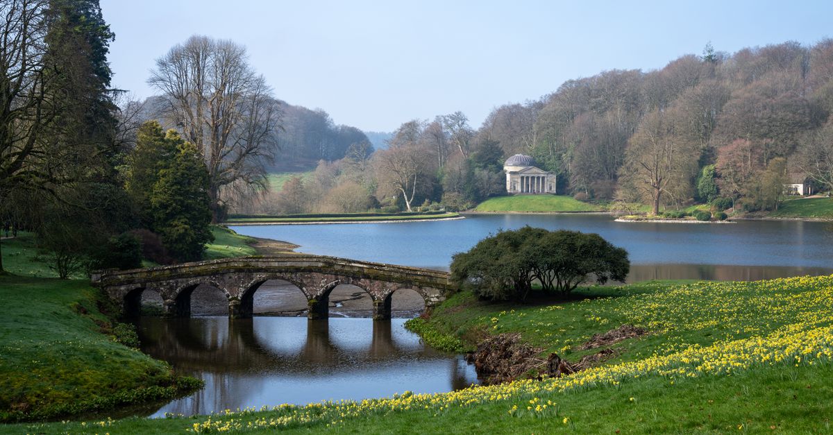 Picturesque view of Stourhead Gardens with classic bridge and lake in spring.
