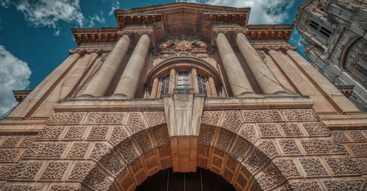 Low angle view of a historic building facade with columns in Bristol, England under a cloudy sky.