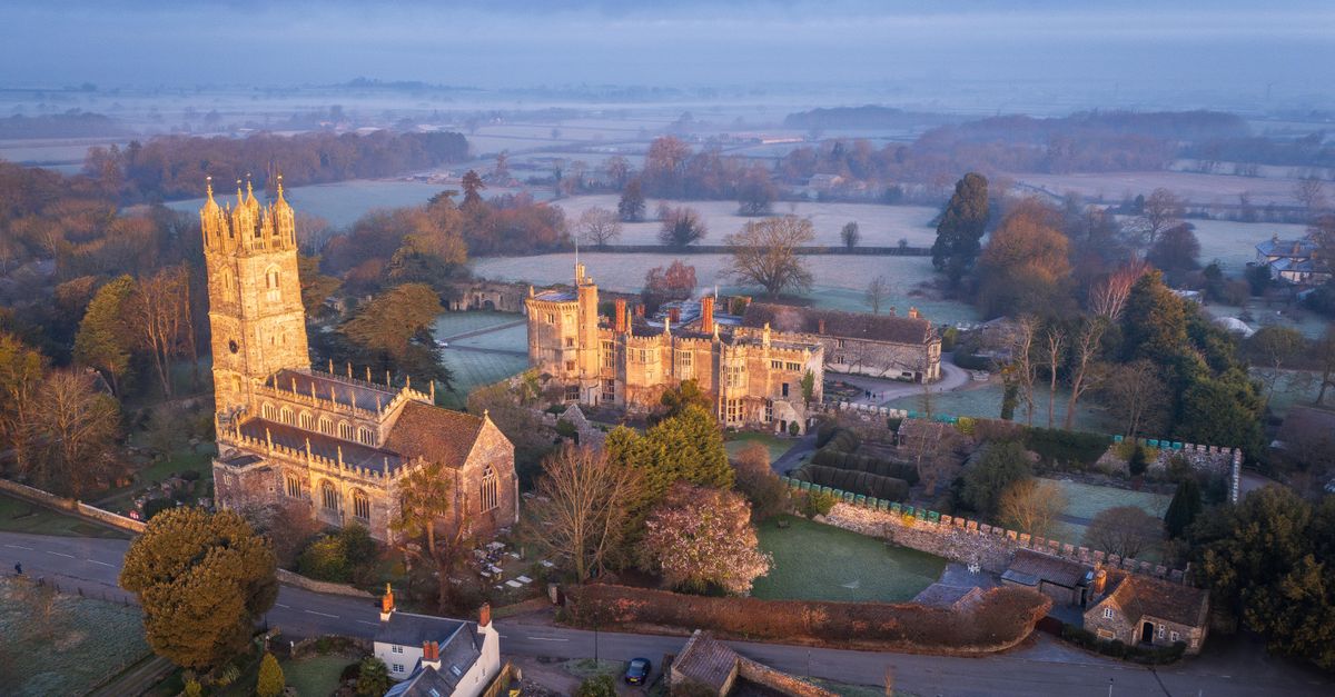 Aerial view of Thornbury Castle in England surrounded by lush countryside at dawn.