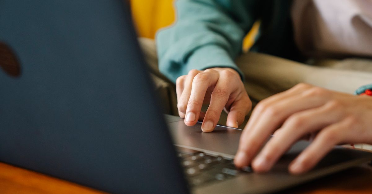 Hands typing on a laptop keyboard, booking travel online