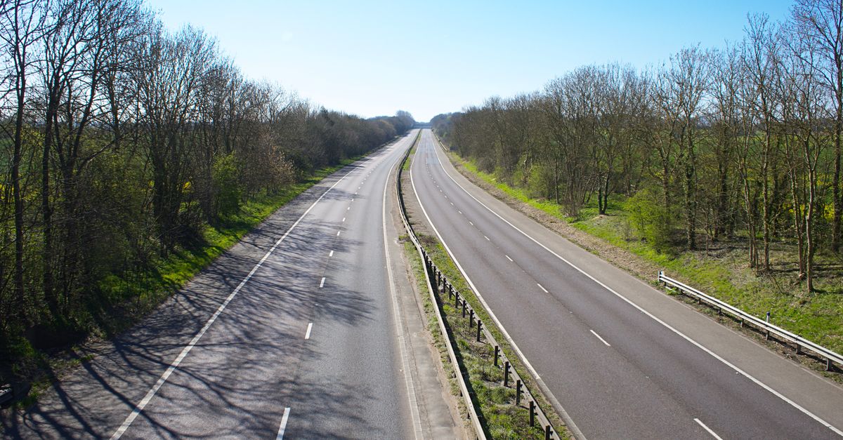 A dual-carriageway cutting through English countryside under a clear sky.