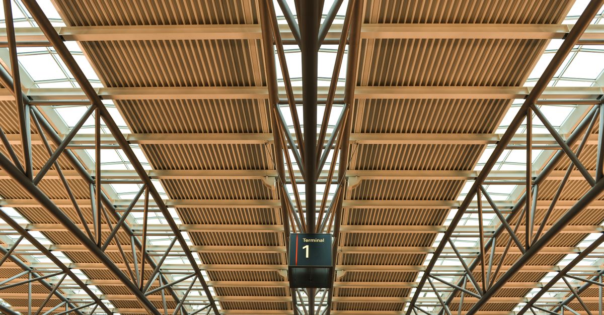 A modern airport terminal roof structure with a 'Terminal 1' wayfinding sign.