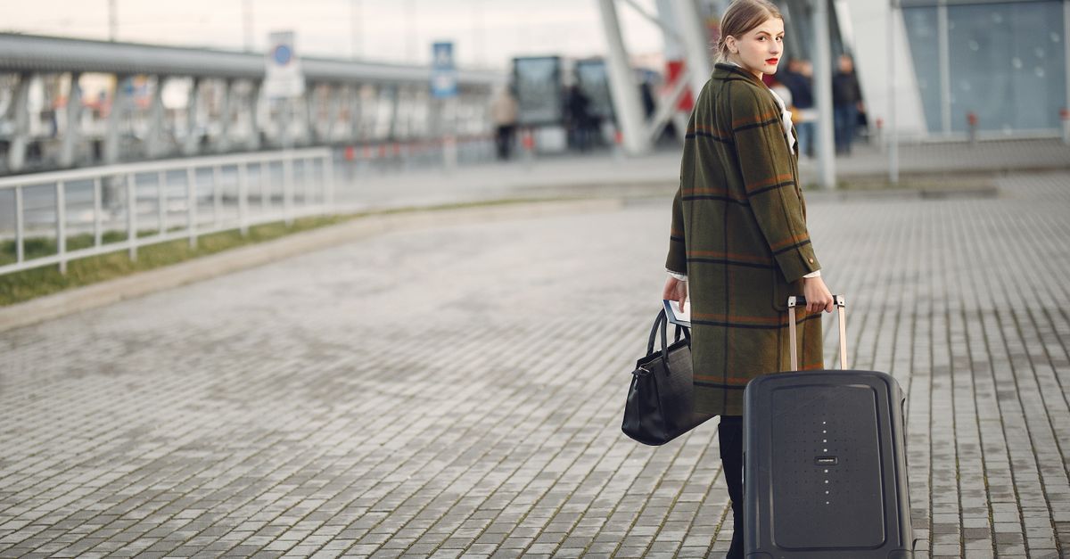 Traveller with a suitcase waiting outside a generic airport terminal entrance