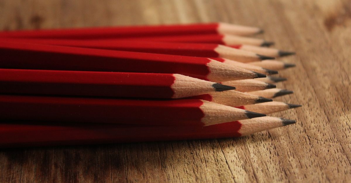 A collection of red pencils neatly arranged on a wooden surface, showcasing sharp tips.
