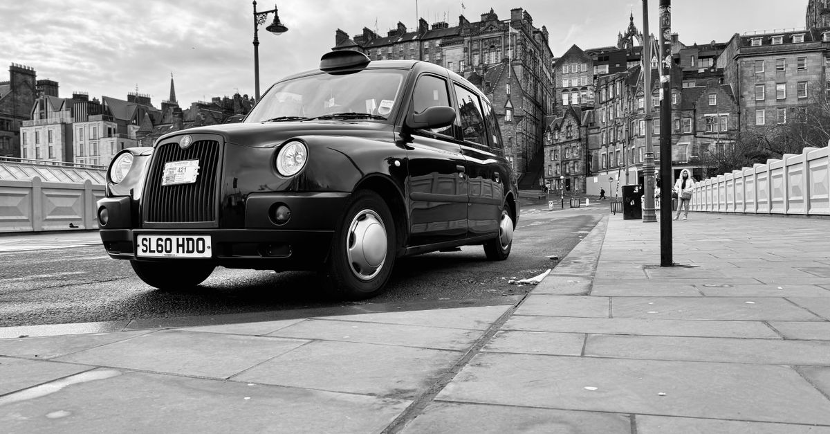 A classic UK black cab (TX4), the wheelchair-accessible taxi model, parked on a city street.